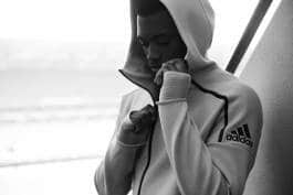 Serious boy is zipping up his hood 